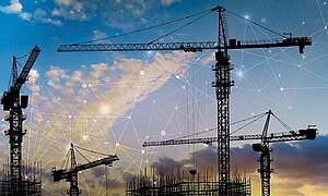 Cranes on construction site at sundown with network graphic