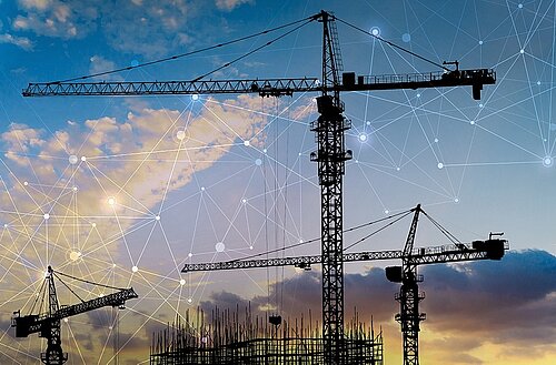 Cranes on construction site at sundown with network graphic